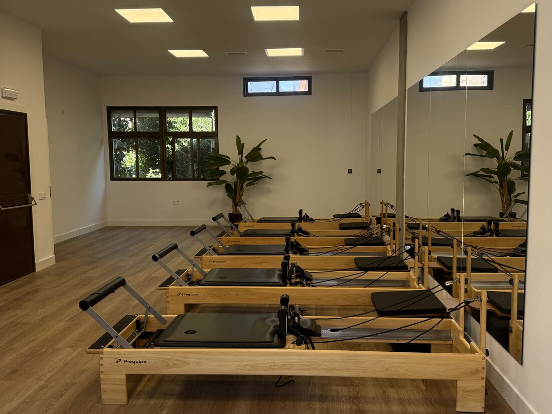 Alumna en su primera clase de pilates en Reformer, guiada por instructora en estudio luminoso